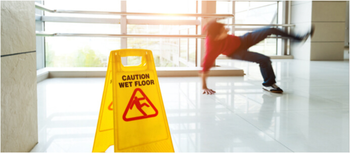 Wet floor sign with person slipping in background